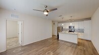 Located at 16333 Columns Way in Baton Rouge, Louisiana, this well-appointed one-bedroom, one-bathroom residence offers a thoughtfully designed single-floor layout. The open-concept living and kitchen area serves as the heart of the home, featuring warm wood-look vinyl flooring, a ceiling fan with light fixture, and a seamless flow between spaces. The kitchen is a standout, equipped with white shaker cabinetry, a subway tile backsplash, granite countertops, a center island with a sink, stainless steel appliances including a refrigerator, range, and microwave, and stylish pendant and track lighting overhead. A hallway leads to the private quarters, showcasing an arched niche detail and convenient access to the laundry room, which houses a full-size washer and dryer. The spacious bedroom is finished with plush carpet and features multiple windows with blinds that invite natural light. A generous walk-in closet with wire shelving provides ample storage. The bathroom offers a granite-topped vanity with white cabinetry, a tiled tub-shower combination, and wood-look flooring, completing this clean and functional home.