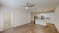 Located at 16333 Columns Way in Baton Rouge, Louisiana, this well-appointed one-bedroom, one-bathroom residence offers a thoughtfully designed single-floor layout. The open-concept living and kitchen area serves as the heart of the home, featuring warm wood-look vinyl flooring, a ceiling fan with light fixture, and a seamless flow between spaces. The kitchen is a standout, equipped with white shaker cabinetry, a subway tile backsplash, granite countertops, a center island with a sink, stainless steel appliances including a refrigerator, range, and microwave, and stylish pendant and track lighting overhead. A hallway leads to the private quarters, showcasing an arched niche detail and convenient access to the laundry room, which houses a full-size washer and dryer. The spacious bedroom is finished with plush carpet and features multiple windows with blinds that invite natural light. A generous walk-in closet with wire shelving provides ample storage. The bathroom offers a granite-topped vanity with white cabinetry, a tiled tub-shower combination, and wood-look flooring, completing this clean and functional home.