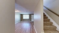 Located in Cortland, NY, this two-story home offers a practical and comfortable layout spread across two floors. The main level features a welcoming living room with light hardwood-style flooring, neutral-toned walls, a baseboard heating system, and a large window dressed with vertical blinds that allows natural light to fill the space. A carpeted staircase connects the two levels. The galley-style kitchen is well-appointed with rich wood cabinetry lining both walls, granite-style countertops, black appliances including a refrigerator, electric range, and dishwasher, as well as a window overlooking the exterior. A full bathroom on the upper level features warm tile flooring, a wood-toned vanity with ample storage, and a tub/shower combination. Both bedrooms are located upstairs and are carpeted for comfort. The generously sized primary bedroom is notably spacious and features dual closets with built-in rods, providing excellent storage. The second bedroom offers a large window with outdoor views and baseboard heating. A hallway connects the upper-level rooms. Throughout the home, a consistent neutral color palette and clean finishes create a cohesive, move-in-ready atmosphere.
