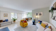 This well-appointed single-floor residence offers a thoughtfully designed layout that balances comfort and functionality. The open-plan living and dining area serves as the heart of the home, bathed in natural light streaming through large windows and a glass-paneled entry door. Light hardwood flooring flows throughout, complementing the neutral white walls accented by a soft sage green dining nook. The living area provides generous space for relaxing and entertaining, while the adjacent dining area offers an intimate setting for shared meals.

The kitchen is efficiently designed with clean white shaker cabinetry, marble-look quartz countertops, a gray subway tile backsplash, and stainless steel appliances and sink — delivering a crisp, modern aesthetic.

Both bedrooms are calm and inviting, featuring carpeted floors, neutral tones, and natural light from windows with garden views. The primary bedroom is generously proportioned, while the second bedroom offers versatility as a guest room or flex space.

The bathroom is finished in an all-white palette, featuring a tub-shower combination, a vanity with marble-look countertop, and clean tile work throughout.

A dedicated home office with a white-painted brick accent wall, a large corner desk, and a bright window overlooking greenery rounds out this functional and stylish space.