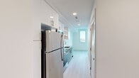 Unit 707 at 777 17th St NE is a thoughtfully designed one-bedroom, one-bathroom residence located on the seventh floor in Washington, DC's Northeast quadrant. Despite its compact footprint, the unit maximizes every inch through an efficient, modern layout with light wood-tone flooring and a crisp white palette throughout.

The galley-style kitchen is well-appointed with stainless steel appliances, including a full-size refrigerator, electric range, over-the-range microwave, and dishwasher. Granite countertops, white subway tile backsplash, and white cabinetry extending to the ceiling provide both style and ample storage.

The main living area benefits from a large picture window offering elevated views of the surrounding Washington, DC cityscape, filling the space with natural light. The spacious primary bedroom features floor-to-ceiling windows and a glass sliding door that opens to a private balcony with panoramic city views, making it a standout feature of the unit.

The bathroom is finished with light wood flooring, a glass-enclosed tiled shower, granite-topped vanity, and open shelving for added storage. A dedicated laundry area houses a stacked full-size washer and dryer, adding practical convenience to this efficiently designed urban residence.