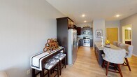 This single-floor residence located on County Road D E in Maplewood, Minnesota offers a well-designed open-concept layout that connects the kitchen, dining, and living areas into one cohesive living space. The kitchen is a standout feature, showcasing rich dark cabinetry that extends to the ceiling, granite countertops, and a full suite of stainless steel appliances including a French door refrigerator, electric range, microwave, and dishwasher. A large granite-topped island provides additional prep space and casual seating, making it a functional centerpiece of the open floor plan.

The living area is bathed in natural light through large sliding glass doors and windows dressed with sheer curtains, offering views of the surrounding outdoor greenery. Light hardwood-style flooring runs throughout the main living areas, complementing the soft blue-gray wall tones and creating a bright, airy ambiance.

The bedrooms feature plush carpeting and generous windows that allow ample natural light. The bathroom is well-appointed with a dual-sink vanity topped with granite, dark cabinetry, a wide mirror, and contemporary light fixtures, providing both style and practicality. Overall, the space presents a modern, comfortable aesthetic with quality finishes throughout.