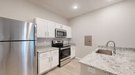 Located at 1007 S English Station Rd in Louisville, KY, this single-story 1-bedroom, 1-bathroom unit offers a thoughtfully designed layout with modern finishes throughout. Light wood-style flooring flows seamlessly across every room, complemented by neutral gray walls and crisp white trim that create a clean, contemporary aesthetic.

The kitchen is a functional highlight, featuring white shaker-style cabinetry with brushed nickel hardware, granite countertops with a speckled pattern, and a full suite of stainless steel appliances including a refrigerator, electric range, and over-the-range microwave. A kitchen island provides additional counter space and doubles as a casual dining or prep area.

The living room is bright and inviting, highlighted by a ceiling fan with light fixture and a set of French doors that allow natural light to fill the space. The bedroom is a comfortable size, offering a window with blinds and access to a dedicated closet.

The bathroom continues the consistent design language with white cabinetry, granite countertops, and light flooring. A hallway connects the rooms efficiently, contributing to the unit's practical flow. Overall, this space presents a modern, move-in-ready environment with quality finishes at every turn.