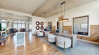 This single-story community clubhouse offers a well-appointed, multi-functional layout encompassing seven distinct areas designed for both social and practical use. The welcoming reception and leasing area greets visitors with soaring vaulted ceilings, wood-look tile flooring, elegant pendant lighting, and a herringbone wood-paneled accent wall. Decorative gear-shaped mirrors add a distinctive design touch above the leasing desks, which are accompanied by contemporary upholstered seating.

The main lounge features expansive floor-to-ceiling windows with transom panels that flood the space with natural light and provide direct views of the outdoor pool area. Built-in shelving, warm wood flooring, and refined furnishings create an inviting atmosphere throughout.

A dedicated business center/office area offers carpeted seating, built-in workstations, and ample natural light, making it ideal for productivity. The catering kitchen is a standout feature, showcasing bold grey subway tile backsplash, quartz countertops, dark cabinetry, and geometric pendant lighting — all oriented toward the pool view.

The expansive fitness center is equipped with a comprehensive range of strength and cardio equipment, floor-to-ceiling mirrors, patterned carpet tile flooring, and large windows that bring in natural light, creating an energizing workout environment.