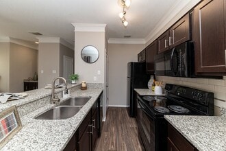 Kitchen with granite counters, black appliances, and modern cabinetry - The Indigo at Grissom