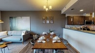 This single-floor residence in Spokane, Washington offers a thoughtfully designed open layout that seamlessly connects the main living areas. The kitchen is a standout feature, equipped with dark espresso cabinetry, stainless steel appliances including a range, microwave, and refrigerator, dark countertops, and a stone tile backsplash — all set atop durable wood-look flooring. A peninsula with pendant lighting connects the kitchen to the dining area, which accommodates a full-sized dining table beneath a chandelier. The living room is bright and inviting, with large windows that invite natural light and provide views of the surrounding landscape, complemented by access to an outdoor area. Two well-proportioned bedrooms feature carpeted floors, generous windows — one with scenic open views — and built-in closet storage. Two full bathrooms each include a tub/shower combination with chrome fixtures. A dedicated in-unit laundry room houses a full-sized washer and dryer with shelving above. A hallway connects the living areas to the private quarters, completing this functional and contemporary single-level layout.