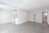 Located at 11424 Killion St in Los Angeles, CA, this single-floor residence offers a clean, modern aesthetic with a practical and comfortable layout. The living area is open and airy, featuring warm wood-look laminate flooring, neutral warm-gray walls, recessed lighting, and a wall-unit heater and air conditioner, ensuring year-round comfort. Large windows dressed with vertical blinds fill the space with natural light and offer views of the surrounding greenery. The entry area welcomes you with a full-lite front door alongside sliding glass doors, further enhancing the sense of openness. The kitchen is semi-open to the living space, separated by a half-wall partition that adds architectural interest while maintaining visual connectivity. It is outfitted with white cabinetry, granite-style countertops, a white subway tile backsplash, a stainless steel gas range, a range hood, and a full-size refrigerator, all set on clean tile flooring. The bedroom is generously proportioned, featuring the same warm laminate flooring, recessed lighting, and a large window with vertical blinds that invites ample natural light. Throughout, the space maintains a consistent, freshly updated palette that conveys a bright and welcoming atmosphere.