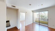 This 1-bedroom, 1-bathroom residence is thoughtfully laid out across a single floor, making efficient use of its compact footprint. Warm hardwood flooring flows continuously throughout, lending a cohesive and inviting character to every room.

The combined kitchen and living area serves as the heart of the home. The kitchen is outfitted with rich wood cabinetry, dark countertops, and a full suite of stainless steel appliances — including a refrigerator, range, and microwave — illuminated by modern track lighting overhead. A breakfast bar provides additional counter space and a natural transition into the living area. The living room is bright and open, featuring clean white walls and a full-width sliding glass door that opens onto a private balcony with views of the surrounding neighborhood and tree canopy.

The bedroom is a well-proportioned retreat with corner windows on two walls, filling the room with natural light and offering pleasant views of the outdoors. Hardwood floors continue here, and the clean, neutral palette creates a calm and restful atmosphere.

The bathroom features a full bathtub and shower combination with white tile surround, maintaining the clean and functional aesthetic found throughout the unit. A hallway connects the primary spaces, adding a sense of separation and privacy. The overall design is modern, clean, and move-in ready.