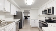 This two-story, three-bedroom, three-bathroom home in Alexandria, Virginia offers a well-organized layout across two floors. The main level provides the larger share of living space and includes a bright living room with a ceiling fan and access to natural light through sliding glass doors, along with a dedicated hallway and staircase connecting both levels. The kitchen is a standout feature, equipped with white shaker-style cabinetry, light quartz countertops, and a full suite of stainless steel appliances including a refrigerator, dishwasher, microwave, and range. Light hardwood-style flooring runs throughout the main living areas, lending a clean and cohesive aesthetic. Upstairs, an open hallway with sleek dark metal railings leads to the bedrooms. The generously sized primary bedroom includes a sliding mirror closet and dedicated bathroom access. The additional bedrooms feature carpet flooring, wide strip windows with outdoor tree views, and ample closet space. All three bathrooms are finished in a clean, white palette with tub-shower combinations. Textured ceilings are consistent throughout the home. Each bedroom includes its own closet, and the layout provides practical flow between living, dining, and sleeping areas.