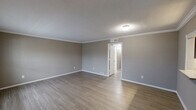 This single-story, 2-bedroom, 2-bathroom home in Galveston, Texas offers a well-organized layout that maximizes functionality throughout. The interior is finished with consistent luxury vinyl plank flooring in the main living areas and hallway, complemented by neutral gray walls and crisp white crown molding and baseboards that lend a clean, polished look to each room.

The combined dining and living area provides a comfortable, open gathering space, while the galley-style kitchen is outfitted with rich dark-brown cabinetry, light quartz countertops, and stainless steel appliances, including a range and over-the-range microwave. A window at the end of the kitchen fills the space with natural light, and a pantry offers additional storage.

The spacious primary bedroom features warm-toned walls and hardwood-style flooring, with ample room for a full furniture arrangement. The second bedroom is carpeted and includes a ceiling fan with light fixture and French doors that invite natural light. Each bedroom is served by a dedicated closet. Both bathrooms are finished with white tile surrounds and tub-shower combinations with brushed nickel fixtures.

Additional conveniences include a dedicated laundry room and a hallway connecting all areas of the home seamlessly. The layout is practical and efficient, suited for comfortable everyday living in a coastal Texas setting.