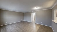 This single-story, 2-bedroom, 2-bathroom home in Galveston, Texas offers a well-organized layout that maximizes functionality throughout. The interior is finished with consistent luxury vinyl plank flooring in the main living areas and hallway, complemented by neutral gray walls and crisp white crown molding and baseboards that lend a clean, polished look to each room.

The combined dining and living area provides a comfortable, open gathering space, while the galley-style kitchen is outfitted with rich dark-brown cabinetry, light quartz countertops, and stainless steel appliances, including a range and over-the-range microwave. A window at the end of the kitchen fills the space with natural light, and a pantry offers additional storage.

The spacious primary bedroom features warm-toned walls and hardwood-style flooring, with ample room for a full furniture arrangement. The second bedroom is carpeted and includes a ceiling fan with light fixture and French doors that invite natural light. Each bedroom is served by a dedicated closet. Both bathrooms are finished with white tile surrounds and tub-shower combinations with brushed nickel fixtures.

Additional conveniences include a dedicated laundry room and a hallway connecting all areas of the home seamlessly. The layout is practical and efficient, suited for comfortable everyday living in a coastal Texas setting.