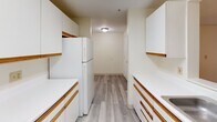 This 3-bedroom, 2-bathroom apartment at 195 Eastern Ave in Manchester, NH offers a practical and well-organized single-floor layout. The unit features a galley-style kitchen equipped with white cabinetry accented by wood-tone trim, a coil-burner electric range, dishwasher, and full-size refrigerator, all set on durable light wood-look flooring that extends through the entryway and hallway. The primary bedroom offers a comfortable amount of space, featuring soft carpeting, a double-door closet, and baseboard heating, with additional bedrooms similarly carpeted and heated. One secondary bedroom benefits from multiple windows that bring in natural light and offer views of surrounding greenery. Both bathrooms are finished with light wood-look flooring, white vanities with wood-trim detailing, and full tub-shower combinations. The neutral white walls and trim throughout the unit create a clean, consistent aesthetic. Baseboard heating is present in the living areas and bedrooms, ensuring efficient warmth. A connecting hallway links the bedrooms and bathrooms, contributing to a logical and easy-to-navigate floor plan. The entrance provides a welcoming transition into the main living areas, rounding out this functional and comfortable residential unit.