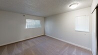 This single-floor, 2-bedroom residence offers a functional and comfortable layout designed to maximize everyday living. The main living area features light-toned hardwood-style flooring, a classic fireplace as a focal point, and a sliding glass door that opens to an outdoor area, allowing natural light to flow through and providing seamless indoor-outdoor connectivity. The textured ceilings are consistent throughout the space, adding a distinctive architectural detail.

The kitchen is efficiently positioned adjacent to the living area and includes standard appliances and cabinetry, offering a practical workspace.

Both bedrooms are carpeted and generously proportioned, with the primary bedroom being notably spacious. Each bedroom is equipped with a closet featuring sliding or standard doors with built-in hanging rods, providing ample storage. Natural light enters through blinds-fitted windows, creating a bright yet controllable environment in each room.

The neutral color palette of white and warm beige tones throughout the walls, ceilings, and floors gives the space a clean, versatile aesthetic suitable for a variety of furnishing styles. Overall, this residence combines practical design with comfortable living spaces in a compact yet efficient single-level floor plan.