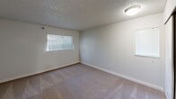 This single-floor, 2-bedroom residence offers a functional and comfortable layout designed to maximize everyday living. The main living area features light-toned hardwood-style flooring, a classic fireplace as a focal point, and a sliding glass door that opens to an outdoor area, allowing natural light to flow through and providing seamless indoor-outdoor connectivity. The textured ceilings are consistent throughout the space, adding a distinctive architectural detail.

The kitchen is efficiently positioned adjacent to the living area and includes standard appliances and cabinetry, offering a practical workspace.

Both bedrooms are carpeted and generously proportioned, with the primary bedroom being notably spacious. Each bedroom is equipped with a closet featuring sliding or standard doors with built-in hanging rods, providing ample storage. Natural light enters through blinds-fitted windows, creating a bright yet controllable environment in each room.

The neutral color palette of white and warm beige tones throughout the walls, ceilings, and floors gives the space a clean, versatile aesthetic suitable for a variety of furnishing styles. Overall, this residence combines practical design with comfortable living spaces in a compact yet efficient single-level floor plan.
