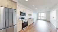 This contemporary 890 square foot apartment, located at 219 9th Ave in Oakland, offers a harmonious blend of style and functionality. The unit boasts two bedrooms, including a spacious primary bedroom of 180 square feet, and one well-appointed bathroom. The open-concept layout maximizes the living space, seamlessly connecting the living room and kitchen areas.

The kitchen is a standout feature, showcasing modern appliances, sleek cabinetry in a mix of white and light wood finishes, and a stylish subway tile backsplash. Warm wood flooring throughout adds a touch of elegance and continuity to the space.

Large windows flood the apartment with natural light and frame breathtaking waterfront views, creating a serene ambiance. The bathroom is designed with clean lines and contemporary fixtures, including a bathtub-shower combination.

This seventh-floor unit (#703) benefits from its elevated position, offering panoramic vistas of the surrounding area. The building's location provides easy access to nearby amenities and green spaces, as evidenced by the landscaped areas visible from the apartment.

With its modern design, efficient use of space, and stunning views, this apartment represents urban living at its finest in the heart of Oakland.