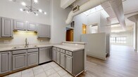 Located at 1300 West 9th Street in Cleveland's dynamic Ohio City neighborhood, this 2-bedroom, 2-bathroom loft-style residence showcases a compelling blend of industrial character and modern finishes. Soaring ceilings with exposed ductwork and structural beams set a dramatic tone throughout the open living areas, which feature light hardwood flooring that enhances the sense of spaciousness and airiness. A large industrial-style window in the living room frames city views while flooding the space with natural light, complemented by a striking exposed brick accent wall that adds warmth and texture.

The well-appointed kitchen features gray shaker-style cabinetry, light countertops, stainless steel appliances, tile flooring, and a peninsula that provides additional workspace and casual seating. A sputnik-style chandelier adds a contemporary touch overhead.

The two bedrooms offer comfortable, carpeted retreats with ample wall space and loft-style architectural details including exposed beams. Both full bathrooms are finished with tile flooring, vanity cabinetry, and tub/shower combinations. Carpeted staircases connect the various levels of the unit, and a dedicated utility room provides practical storage. The overall aesthetic is a refined urban loft that balances industrial heritage with everyday livability.