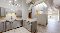Located at 1300 West 9th Street in Cleveland's dynamic Ohio City neighborhood, this 2-bedroom, 2-bathroom loft-style residence showcases a compelling blend of industrial character and modern finishes. Soaring ceilings with exposed ductwork and structural beams set a dramatic tone throughout the open living areas, which feature light hardwood flooring that enhances the sense of spaciousness and airiness. A large industrial-style window in the living room frames city views while flooding the space with natural light, complemented by a striking exposed brick accent wall that adds warmth and texture.

The well-appointed kitchen features gray shaker-style cabinetry, light countertops, stainless steel appliances, tile flooring, and a peninsula that provides additional workspace and casual seating. A sputnik-style chandelier adds a contemporary touch overhead.

The two bedrooms offer comfortable, carpeted retreats with ample wall space and loft-style architectural details including exposed beams. Both full bathrooms are finished with tile flooring, vanity cabinetry, and tub/shower combinations. Carpeted staircases connect the various levels of the unit, and a dedicated utility room provides practical storage. The overall aesthetic is a refined urban loft that balances industrial heritage with everyday livability.
