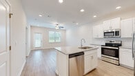 This well-designed 2-bedroom, 2-bathroom single-story home offers a bright and modern living experience. The open-concept kitchen and living area serves as the heart of the home, featuring light hardwood-style flooring, recessed lighting, and a ceiling fan. The kitchen is outfitted with white shaker cabinetry, granite countertops, a central island with a built-in sink and dishwasher, and a full suite of stainless steel appliances including a range, microwave, and refrigerator. The living area benefits from natural light provided by large windows with blinds and direct access to the exterior.

Both bedrooms are carpeted and include ceiling fans, offering a comfortable and quiet retreat. The primary bedroom is a generous size with a dedicated closet. The two bathrooms maintain a consistent design language, featuring granite-topped vanities, white cabinetry, and hardwood-style flooring. One bathroom includes a soaking tub and shower combination, while the other features a glass-enclosed walk-in shower. Throughout the home, a neutral color palette of whites and soft beiges creates a clean, cohesive, and move-in-ready aesthetic.