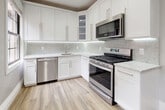 Located at 35-09 191st Street in Flushing, NY, this single-floor residence combines classic architectural details with modern updates throughout. Rich, dark-stained hardwood floors run consistently across the living areas and bedrooms, reflecting natural light and adding warmth to each room. Crown molding frames the ceilings throughout, complementing the clean white baseboards and neutral gray walls to create a refined, cohesive aesthetic.

The main living area is generously proportioned, featuring two windows that invite ample natural light, a ceiling fan with integrated lighting, and recessed fixtures. An elegant arched doorway provides a graceful transition between rooms. A secondary room offers similar finishes, with a single window, ceiling fan, and a classic cast-iron radiator beneath the sill.

Additional rooms feature double six-panel doors, recessed lighting, and ceiling fans, providing flexible use of space. The kitchen has been thoughtfully updated with white shaker-style cabinetry, light quartz countertops, a marble-style tile backsplash, and a full suite of stainless steel appliances, including a gas range, dishwasher, and over-range microwave. Light wood-tone tile flooring completes the bright, modern kitchen aesthetic.