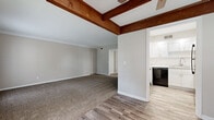 Located at 7200 Eby Dr in Merriam, Kansas, this 2-bedroom, 1-bathroom single-story home offers a well-designed layout with a variety of thoughtful finishes throughout. The living area is a standout space, featuring rich, dark wood exposed beams set against a coffered ceiling, complemented by a ceiling fan and an abundance of natural light streaming through large windows and a glass-paneled door. The transition from plush carpet in the living area to light wood-style luxury vinyl flooring in the adjoining spaces creates a welcoming flow throughout the home. The kitchen is well-appointed with crisp white shaker-style cabinetry, light stone countertops, a subway tile backsplash, and stainless steel and black appliances, including a refrigerator, dishwasher, and range. The spacious primary bedroom includes a walk-in closet and recessed lighting, while the second bedroom benefits from dual windows that invite ample natural light. The bathroom features white cabinetry with modern hardware, a countertop sink, and wood-style flooring, maintaining a clean and consistent aesthetic. Crown molding and neutral tones are present throughout, contributing to a cohesive and move-in-ready feel.