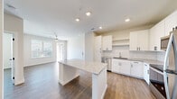 Located at 2300 N Broad St in Fuquay-Varina, NC, this thoughtfully designed single-floor home offers a clean, modern aesthetic with an efficient and functional layout. The open-concept kitchen and living area serves as the heart of the home, featuring crisp white shaker cabinets, a subway tile backsplash, granite countertops, and stainless steel appliances including a dishwasher, range, microwave, and refrigerator. A central kitchen island with matching granite provides additional prep space and casual seating. Recessed lighting illuminates the area, which flows seamlessly into the living room. The living space is bright and airy, benefiting from large windows and a glass door that invite abundant natural light and offer views of the surrounding neighborhood. A ceiling fan adds comfort to the living area. Wood-style flooring runs throughout the home, lending warmth and continuity. The bedroom is a comfortable, well-proportioned retreat with large windows and direct access to the walk-in closet, which is equipped with built-in wire shelving for organized storage. The full bathroom features a tub-shower combination with tile surround, a granite-topped vanity, and direct access to the walk-in closet. The entrance provides a welcoming transition into the home, completing this well-appointed and move-in-ready residence.