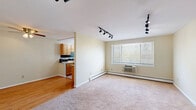 This single-floor residence offers a practical and well-organized layout across three bedrooms, one bathroom, and a dedicated kitchen. The open living area greets you upon entry, featuring soft carpeted flooring, black track lighting overhead, and a large window that invites natural light while providing outdoor views. Baseboard heating and a wall-mounted air conditioning unit ensure year-round comfort. The kitchen is a standout feature, showcasing warm honey-toned cabinetry, granite countertops, a bold dark tile backsplash with decorative accents, stainless steel appliances, and tile flooring — all centered around a bright window. The generously sized primary bedroom offers ample space, track lighting, and a well-organized closet with built-in wire shelving. The additional bedrooms are carpeted and well-lit, each featuring track lighting, baseboard heating, and closet access. The full bathroom is clean and functional, finished with light tile flooring, a vanity with under-sink storage, and a tub-shower combination enclosed by sliding glass doors. Throughout the residence, warm cream-toned walls and consistent finishes create a cohesive and comfortable living environment.
