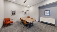 Located at 410 W Lake Street in Minneapolis, MN, this contemporary lobby and common area space offers a thoughtfully designed, single-floor layout that blends industrial and modern aesthetics. The main entry is immediately striking, with soaring ceilings that expose structural ductwork and pipes overhead, polished concrete floors, and a dramatic white-tile-clad fireplace framed in sleek black. A vibrant, colorful art piece anchors the entry wall, set against light wood paneling, while a globe chandelier adds a warm, inviting glow near large windows that draw in natural light and offer views of the surrounding West Lake Street neighborhood.

The lobby flows into a dedicated mail and package area, where an array of individual mailboxes lines a teal-accented wall with geometric patterned wallcovering, complemented by a convenient Amazon Hub package locker station. Built-in cabinetry with clean white countertops provides additional functionality throughout the common corridors.

A private conference room offers a quiet, professional setting furnished with a wood-top table, upholstered rolling chairs, and pendant lighting, making it ideal for meetings or focused work. The overall design palette—polished concrete, white tile, muted grays, and warm wood tones—creates a cohesive, contemporary atmosphere that is both functional and welcoming for residents and visitors alike.