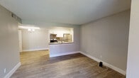 This single-floor unit offers a clean, modern layout designed for comfortable everyday living. The open-concept living area is finished with wood-look luxury vinyl plank flooring and neutral gray walls, creating a bright and cohesive atmosphere throughout. A textured ceiling adds character to the living space, which flows seamlessly toward the kitchen.

The kitchen is accessible via a pass-through counter with a dark laminate surface, ideal for casual dining or meal prep. Inside, white shaker-style cabinetry provides ample storage, complemented by a metallic tile backsplash and stainless steel appliances including a refrigerator, electric range, and double-basin sink. A skylight-style overhead fixture brightens the kitchen corridor, which features additional cabinetry on both sides for generous storage. A chandelier-style light fixture is visible from the kitchen, adding an elegant touch to the dining area.

The bedroom is a tranquil, well-proportioned room with the same wood-look flooring, neutral walls, a window with blinds allowing natural light, and a ceiling fan for year-round comfort.

The bathroom is finished with tile flooring, a white tub-shower combination with a curved curtain rod, and clean, neutral tones throughout. The overall design of the unit is functional, modern, and move-in ready.