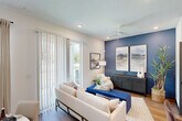 Located at 100 Inspire Way in St. Augustine, FL, this two-story home offers a thoughtfully designed layout spread across two floors. The main level features an open-concept kitchen and living area anchored by a bold navy accent wall, recessed lighting, and large sliding glass doors that flood the space with natural light. The kitchen is appointed with white shaker cabinetry, granite countertops, a subway tile backsplash, and stainless steel appliances. A garage and laundry room with full-size washer and dryer complete the ground floor. Upstairs, the more expansive floor hosts both bedrooms, all three bathrooms, a hallway, and two closets. The generously sized primary bedroom features a tray ceiling, plush carpet, a teal accent wall, and access to a walk-in closet with built-in shelving and a full-length arched mirror. The bathrooms are finished with granite vanities, wood-look flooring, subway tile, and matte black fixtures throughout — one offering a glass-enclosed walk-in shower with open shelving, and another featuring a classic soaking tub. The exterior presents a clean, contemporary facade with lap siding, an attached garage, and landscaped grounds backed by mature trees.