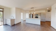 This single-floor unit showcases a clean, contemporary design with a cohesive neutral palette and dark hardwood-style flooring that flows throughout the space. The open-concept living and kitchen area serves as the heart of the unit, centered around a spacious white kitchen island with an undermount sink and pendant lighting overhead. The kitchen is well-appointed with wood-toned flat-front cabinetry, a white subway tile backsplash, and a full suite of stainless steel appliances including a refrigerator, electric range, and microwave. A secondary sink station is positioned along an adjacent wall, offering added convenience.

The bedrooms are bright and well-proportioned, each featuring large framed windows that invite generous natural light and views of surrounding greenery and streetscapes. The crisp white walls and wood-style flooring carry through each room, maintaining a consistent, modern aesthetic.

Two bathrooms serve the unit. The primary bathroom features a dual-sink vanity with wood-grain cabinetry, quartz countertops, and a glass-enclosed walk-in shower. The secondary bathroom includes a single vanity with matching finishes and a full tub-shower combination. Both bathrooms are finished with brushed nickel fixtures and large mirrors, contributing to a bright, polished feel throughout.
