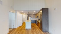 This well-appointed two-story residence showcases a thoughtful layout and contemporary finishes throughout. The heart of the home is an open-concept kitchen, designed for both function and style. It features a large center island topped with light granite countertops, dual pendant lights, and an array of two-toned cabinetry — light wood upper cabinets paired with darker lower cabinets for a modern contrast. A full suite of stainless steel appliances includes a refrigerator, range, microwave, and dishwasher, complemented by a classic subway tile backsplash. Warm hardwood flooring extends through the main living areas, which benefit from soaring double-height ceilings that create a striking sense of openness and volume. A sliding glass door with vertical blinds provides access to an outdoor area and fills the living space with natural light. Upper-level bedrooms are finished with plush neutral carpeting, each equipped with a ceiling fan and windows fitted with blinds. A bathroom features a granite-topped vanity with an undermount sink and a clean, neutral color palette. Throughout the residence, recessed lighting, clean white walls, and consistent attention to detail contribute to a bright, modern, and move-in-ready atmosphere.