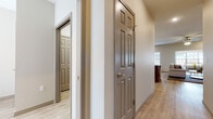 This single-story residence at 849 West Logan Street in Rogersville, Missouri, presents a thoughtfully designed layout with a cohesive neutral color palette and a mix of light wood-look flooring and plush carpeting throughout. The interior hallways are distinguished by six-panel doors with brushed nickel hardware, contributing to a clean, consistent aesthetic that flows through the home.

The living room is a comfortable, well-lit space featuring recessed lighting, a ceiling fan, and multiple windows that invite natural light. It opens toward a dedicated sitting or sunroom area, also bathed in natural light through large windows, offering a relaxed retreat. The dining area accommodates a full dining set and features warm taupe accent walls alongside a window for additional brightness.

The kitchen is well-equipped with rich dark cabinetry, light granite countertops, black appliances including an electric range with an overhead vent hood, and light wood-look flooring—providing both function and style. Bedrooms feature plush carpeting and vaulted ceilings, with access to generously sized walk-in closets outfitted with multi-tier wire shelving systems. The overall ambiance is clean, modern, and move-in ready.
