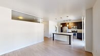 This well-designed single-floor unit offers a clean, contemporary aesthetic throughout. The entryway hallway sets the tone with light wood-style flooring, crisp white walls, and a stylish sliding barn door that adds a modern industrial touch while maximizing usable space.

The open-concept kitchen and living area forms the heart of the unit. The kitchen is outfitted with rich dark-toned cabinetry, granite countertops, and a full suite of stainless steel appliances including a refrigerator, electric range, and over-the-range microwave. A large kitchen island with a double-basin sink and pendant lighting above serves as both a functional workspace and a natural gathering point. Track lighting provides additional illumination over the cooking area. Conveniently tucked behind the kitchen is an in-unit stacked washer and dryer.

The living area is bright and open, featuring light hardwood-style flooring and a neutral color palette that promotes a calm, airy atmosphere. A mirrored accent detail on one wall adds visual depth to the space.

The bedroom offers plush carpeting, dual sets of closets providing generous storage, and windows with roller shades that offer views of the surrounding neighborhood. Throughout the unit, clean lines, neutral tones, and thoughtful finishes create a cohesive and inviting living environment.