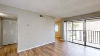 Located at 7950 Shoals Drive in Orlando, Florida, this single-floor residence offers a well-organized layout with a clean, contemporary aesthetic throughout. The living area is finished with durable wood-style flooring and neutral-toned walls, creating a bright and versatile space. A textured ceiling adds classic character, while large sliding glass doors open directly onto a private balcony, inviting natural light and views of the surrounding Florida greenery, including mature palm trees.

The kitchen is a standout feature, equipped with crisp white shaker-style cabinetry, striking granite countertops with bold veining, and stainless steel appliances, including a range with overhead ventilation. The layout provides functional workspace and ample storage.

The bedrooms are carpeted for comfort, offering a quieter and softer atmosphere. Each room receives natural light through windows, and at least one bedroom includes a dedicated closet with built-in shelving for organized storage.

The bathroom features a full-size soaking tub and shower combination with clean white surrounds. Throughout the unit, a consistent use of neutral tones, white trim, and vertical shiplap wall accents contributes to a cohesive and modern interior design well-suited to the warm Orlando climate.