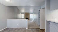 This single-story, 2-bedroom, 3-bathroom home makes efficient use of its well-organized floor plan. The living room is a standout space, featuring soaring vaulted ceilings that lend an open, airy feel well beyond its physical footprint. A floor-to-ceiling brick fireplace with a wood-accented surround serves as the room's focal point, flanked by windows that allow natural light to filter in. Carpet flooring extends across the living area, while wood-look hard flooring defines the entryway and transition zones. A built-in shelving unit provides convenient display and storage space along one wall.

The primary bedroom offers a ceiling fan, sliding glass doors that open to an outdoor area, and access to a generously sized walk-in closet equipped with multi-tier shelving and hanging rods. The second bedroom features carpet, a ceiling fan, and its own closet with built-in shelving. The bathrooms include a vanity with quartz-style countertops and white cabinetry in one, and a tiled tub-shower surround with wood-look tile flooring in another. A dedicated laundry area and a hallway with additional storage round out this thoughtfully laid-out home.
