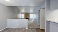 This single-story, 2-bedroom, 3-bathroom home makes efficient use of its well-organized floor plan. The living room is a standout space, featuring soaring vaulted ceilings that lend an open, airy feel well beyond its physical footprint. A floor-to-ceiling brick fireplace with a wood-accented surround serves as the room's focal point, flanked by windows that allow natural light to filter in. Carpet flooring extends across the living area, while wood-look hard flooring defines the entryway and transition zones. A built-in shelving unit provides convenient display and storage space along one wall.

The primary bedroom offers a ceiling fan, sliding glass doors that open to an outdoor area, and access to a generously sized walk-in closet equipped with multi-tier shelving and hanging rods. The second bedroom features carpet, a ceiling fan, and its own closet with built-in shelving. The bathrooms include a vanity with quartz-style countertops and white cabinetry in one, and a tiled tub-shower surround with wood-look tile flooring in another. A dedicated laundry area and a hallway with additional storage round out this thoughtfully laid-out home.