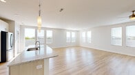 Located in Richmond Heights, Missouri, this well-appointed single-floor residence offers three bedrooms, three bathrooms, and a thoughtfully designed open-concept layout. The expansive living and kitchen area is the heart of the home, characterized by light hardwood flooring, abundant natural light from multiple large windows, and a clean, contemporary aesthetic with crisp white walls. The chef's kitchen is a standout feature, boasting a generous granite-topped island with an undermount sink, light wood cabinetry, white tile backsplash, a stainless steel refrigerator, built-in double wall ovens, a gas cooktop, and a stainless range hood — all illuminated by a row of modern pendant lights. The spacious primary bedroom benefits from a bank of windows offering outdoor views and is complemented by its own closet. Secondary bedrooms include plush carpeting, ceiling fans, and ample natural light. The bathrooms are finished with granite vanities, light wood cabinetry, and built-in shelving. A dedicated laundry room includes a full-size washer and dryer. Three closets provide excellent storage throughout. This residence combines modern finishes with a bright, open ambiance for comfortable everyday living.