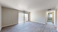 Located in Peoria, Arizona, this 2-bedroom, 1-bathroom single-floor unit offers a clean, modern aesthetic with thoughtfully updated finishes throughout. The open living area is highlighted by wood-style plank flooring in a soft gray tone, neutral painted walls, and a sliding glass door fitted with vertical blinds that fills the space with natural light and provides access to an outdoor patio. The kitchen is well-appointed with crisp white shaker cabinets, white countertops, and a full suite of stainless steel appliances including a refrigerator, electric range, dishwasher, and an overhead range hood, all set atop matching light wood-style flooring. Both bedrooms are carpeted in a neutral tone, offering a comfortable and quiet retreat. The primary bedroom is a generous size and includes a closet, while the second bedroom also features a closet and a window with natural light. The shared full bathroom is finished with wood-style flooring, a white vanity with ample cabinet storage, and a tiled tub-shower combination. Two dedicated closets provide practical storage throughout the unit. The overall design is clean and contemporary, making this a functional and inviting home.