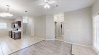 This two-story home offers a well-organized layout spread across two floors, providing ample space for comfortable living. The main level features an open living room and kitchen area with a mix of light wood-look vinyl and tile flooring, complemented by ceiling fans and a neutral color palette throughout. The living room includes a fireplace, adding a focal point to the space, while a tiled hallway connects the main areas and leads to the staircase with carpeted treads.

The kitchen is equipped with dark wood cabinetry, stainless steel appliances including a refrigerator and range, light countertops, and tile flooring, with a window providing natural light. A dedicated laundry room on the main level features tile flooring, built-in shelving, and washer/dryer hookups for added convenience. The attached garage offers a clean, functional space with an automatic door opener.

Upstairs, four bedrooms are finished with plush carpeting and ceiling fans, offering a comfortable and quiet retreat. The generously sized primary bedroom provides notable square footage among the four. Two closets serve the upper level, including a walk-in style closet with built-in hanging rods. Three bathrooms are distributed throughout the home, including tub/shower combinations with tile surrounds and wood-look flooring.