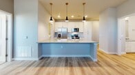 Located at 4700 Wagon Rd in Santa Fe, NM, this single-story, 3-bedroom, 2-bathroom home offers a thoughtfully designed layout with modern finishes throughout. The kitchen serves as the centerpiece of the home, featuring crisp white cabinetry, light quartz countertops, and a light blue accent island with seating. Stainless steel appliances — including a French door refrigerator, electric range, built-in microwave, and dishwasher — complete the space, while three stylish black pendant lights add a contemporary touch. Light wood-look flooring runs through the main living areas, enhancing the bright, clean aesthetic. The primary bedroom offers a comfortable retreat with its own en suite bathroom, which includes a walk-in glass shower, a single vanity with quartz countertops, and wood-look flooring. The secondary bathroom features a tub-shower combo with neutral tile surround. The two additional bedrooms are carpeted and include ceiling fans, closets, and windows that bring in natural light. A utility room and dedicated entrance round out the floor plan. The home's neutral color palette, recessed lighting, and clean architectural lines create a modern, move-in-ready environment ideal for comfortable everyday living.