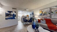 This well-appointed single-floor residence offers a thoughtfully designed open-concept layout that seamlessly connects the living, dining, and kitchen areas. The living room is bright and welcoming, featuring wood-look flooring, a textured ceiling, and a large window that allows natural light to fill the space. Bold abstract artwork adorns the walls, adding a vibrant, contemporary character throughout.

The kitchen is outfitted with white shaker-style cabinetry, light quartz countertops, a grey subway tile backsplash, and stainless steel appliances including a dishwasher, range, and microwave. The adjacent dining area provides a comfortable space for meals, flowing naturally into the living room for an open, connected feel.

The primary bedroom is generously sized with wood-look flooring, a textured ceiling, natural light from a large window, and ample space for full bedroom furnishings. A second bedroom mirrors this comfort, also featuring a window and wood-look flooring. A third flexible room is configured with bunk beds and features a bold geometric area rug, ideal as an additional sleeping or multi-use space.

Two full bathrooms serve the residence, each finished with wood-look tile flooring, white vanities with quartz counters, and shower-tub combinations. The overall design palette — neutral tones accented with navy, rust, and teal — lends the space a modern, cohesive aesthetic.