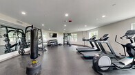 Located at 2305 Sokol Ct in Darien, IL, this dedicated fitness center offers a comprehensive exercise environment designed to support a wide range of workout routines. The single-floor space is thoughtfully laid out to maximize functionality and flow, with durable rubber flooring throughout that provides both safety and comfort during exercise.

The cardio zone features multiple treadmills and an elliptical machine, positioned near windows that allow natural light to fill the space and offer pleasant outdoor views of the surrounding greenery. A large standing fan provides additional air circulation in this area.

The strength training section is well-appointed with a multi-functional cable machine, a Smith machine with an adjustable bench, and a full rack of dumbbells organized on tiered storage. Full-length mirrors line one wall, enhancing the sense of space and allowing users to monitor their form during workouts. A wall-mounted flat-screen TV adds an entertainment element to the training environment.

Additional functional fitness equipment, including stability balls, medicine balls, and a punching bag, is available for varied training. Recessed lighting overhead ensures the space remains bright and well-illuminated at all times. Glass partition doors connect the fitness center to an adjacent lounge area, contributing to an open and accessible feel throughout the facility.
