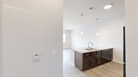 Located at 501 4th Ave SE in Cedar Rapids, Iowa, this two-bedroom, one-bathroom residence offers a thoughtfully designed single-floor layout with a clean, modern aesthetic throughout. Light-toned luxury vinyl plank flooring flows continuously across the living areas and bedrooms, creating a cohesive and bright atmosphere.

The kitchen serves as a centerpiece of the home, featuring a large island with granite countertops, a stainless steel sink, and elegant pendant lighting overhead. Dark espresso cabinetry provides ample storage and contrasts beautifully against the light countertops and white walls. Black appliances, including a refrigerator, range, and microwave, complete the contemporary kitchen design.

Both bedrooms are well-proportioned and bright, with large windows that allow natural light to fill each room. Ceiling fans are installed in the main living and bedroom areas for added comfort. The primary bedroom offers a comfortable footprint with convenient access to adjacent spaces.

The bathroom is finished with a wide vanity, white countertop, large mirror with overhead lighting, and tile-style flooring that adds a clean, polished look. A dedicated laundry area houses a stacked washer and dryer unit, adding everyday convenience to the space. The layout is efficient and functional, making excellent use of every square foot.