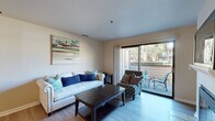 This efficiently designed 2-bedroom, 1-bathroom single-floor residence in Vacaville, CA offers a well-organized layout across a compact footprint. The combined living and dining area serves as the heart of the home, featuring light wood-style flooring, a fireplace with a tile surround, and a sliding glass door that opens to a private balcony with outdoor seating and greenery views. The dining area accommodates a full-sized table and is accented by a ceiling fan. The kitchen is well-appointed with rich dark wood cabinetry, granite countertops, stainless steel appliances including a range, microwave, and refrigerator, plus a deep undermount sink with a window above. The primary bedroom features carpeted flooring, a sliding-door closet, and direct access to the full bathroom. A separate walk-in closet provides additional storage. The bathroom includes dark wood vanity cabinetry with granite counters and a shower-tub combo. The second bedroom is carpeted with natural light from a wide window. A dedicated in-unit laundry area houses a full-sized washer and dryer. A hallway connects all rooms, contributing to a functional and cohesive flow throughout the space.