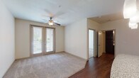 This single-floor residence offers a thoughtfully designed layout that balances comfort and functionality. The open-concept kitchen is a standout feature, showcasing rich dark cabinetry, granite countertops, a central island with pendant lighting, and a full suite of stainless steel appliances, including a range, over-the-range microwave, and refrigerator. The hardwood-style flooring throughout the kitchen and common areas adds warmth and visual continuity to the space.

The living area is generously sized, with plush wall-to-wall carpeting, a ceiling fan, and French doors that invite natural light and provide access to an outdoor area. The bedrooms are equally well-proportioned, each featuring ceiling fans, large windows with blinds, and soft carpeting. One bedroom connects directly to the kitchen area, offering a convenient layout.

The bathroom is finished with a dual-sink vanity topped with granite countertops, dark cabinetry with brushed nickel hardware, a tub-shower combination, and hardwood-style flooring that ties the space together cohesively. Additional storage is provided by a set of double doors near the kitchen, adding practical utility. The overall aesthetic is clean, modern, and move-in ready.