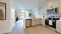 Located at 2314 Berryhill Rd in Charlotte, NC, this one-bedroom, one-bathroom residence offers a thoughtfully designed open-concept layout with modern finishes throughout. Light-toned hardwood-style flooring flows seamlessly across the entire space, enhancing the bright and airy atmosphere created by white walls and ample natural light.

The kitchen is a standout feature, equipped with stainless steel appliances including a refrigerator, range, microwave, and dishwasher. Cream-toned shaker-style cabinetry with matte black hardware pairs with a herringbone tile backsplash and white quartz countertops. A peninsula provides additional workspace and opens directly into the living area, making the layout ideal for both everyday living and entertaining.

The bedroom is a comfortable retreat featuring a ceiling fan, large windows with blinds and sheer curtains admitting generous natural light, and direct access to both a closet and the bathroom. The bathroom is finished with white subway tile, a white shaker vanity with quartz countertops, and matte black hardware accents, maintaining the clean, cohesive aesthetic found throughout the home.

A dedicated closet provides practical storage, and the overall design reflects a modern, neutral palette that is both functional and visually appealing.