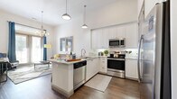 This one-bedroom, one-bathroom residence in Plano, TX offers a thoughtfully designed open-concept layout across a single floor. The kitchen is a standout feature, showcasing crisp white cabinetry, granite countertops, a large peninsula with bar seating, and a full suite of stainless steel appliances including a side-by-side refrigerator, electric range, microwave, and dishwasher. Pendant lighting and rich wood-look flooring add warmth and character to the space. The kitchen flows seamlessly into the living area, which benefits from soaring ceilings, large windows, and a glass sliding door that invites abundant natural light and outdoor views. The bedroom is a comfortable retreat featuring plush carpeting, tall ceilings, a walk-in closet, and a sizable window framing views of the surrounding greenery. The bathroom is well-finished with white shaker cabinetry, a granite vanity top, an undermount sink, and a tiled tub-shower combination with wood-look flooring. A hallway connects the living spaces efficiently. Throughout the residence, a neutral color palette, quality finishes, and high ceilings create a bright, modern, and inviting ambiance.