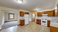Located at 229 S Kendall Ave in Kalamazoo, Michigan, this two-story home offers five bedrooms and two bathrooms across a well-distributed layout. The main floor provides the larger share of the living space and serves as the functional core of the home, anchored by a generously sized kitchen equipped with warm oak cabinetry, light-toned countertops, tile flooring, a gas range, dishwasher, and refrigerator. A laundry area is conveniently accessible from the kitchen. The living room features plush wall-to-wall carpeting and a pair of wood-trimmed windows that allow natural light and views of the surrounding neighborhood. The bathrooms include a full tub/shower combo with a window for natural ventilation and a separate stand-up shower stall. Bedrooms are finished with soft gray carpet and neutral walls, providing a clean, versatile backdrop. The spacious primary bedroom includes a built-in double closet with warm wood-toned doors. Additional bedrooms offer comfortable proportions, some with outdoor-facing windows. The upper floor houses additional bedrooms with angled ceilings that add architectural character. Throughout the home, consistent wood trim, baseboards, and neutral color tones create a cohesive and practical living environment.