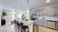 Located at 3755 E McKinney St in Denton, TX, this single-story 2-bedroom, 2-bathroom home offers a thoughtfully designed layout with modern finishes throughout. The open-concept kitchen is a standout feature, boasting gray shaker-style cabinetry, granite countertops, a large center island with pendant lighting, stainless steel appliances including a French door refrigerator, and light hardwood-style flooring that flows seamlessly into the living area. The living room is bright and inviting, with large windows that bring in natural light and create an airy atmosphere. The primary bedroom features plush carpeting, a ceiling fan, and direct access to a private en-suite bathroom complete with a granite vanity, gray cabinetry with black hardware, and a glass-enclosed shower. A generously sized walk-in closet with built-in shelving and dual hanging rods provides excellent storage. The second bedroom is comfortably sized with a window offering natural light and its own closet access. The second bathroom mirrors the home's consistent design aesthetic with matching granite counters and gray cabinetry. Clean white walls, six-panel doors with black hardware, and cohesive finishes throughout lend the home a modern yet welcoming character.