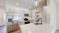 Located at 508 East Genesee Pointe Drive in West Henrietta, NY, this single-floor, 2-bedroom, 1-bathroom home offers a clean, modern aesthetic throughout. The open kitchen is a standout feature, showcasing soft gray shaker-style cabinetry, quartz countertops, a large island with an undermount sink and pendant lighting, and a full suite of stainless steel appliances including a refrigerator, electric range, microwave, and dishwasher. A dedicated in-unit laundry closet with a stacked washer and dryer is conveniently accessible from the kitchen area. Light wood-look flooring runs throughout the main living areas, while the bedrooms feature plush carpet. The living room is bright and airy, highlighted by a sliding glass door that invites natural light and provides outdoor access. The primary bedroom offers generous space, a ceiling fan, a walk-in closet, and direct access to the bathroom, which features a vanity with gray cabinetry, a framed mirror, and wood-look flooring. The second bedroom also benefits from natural light through a large window. Crisp white walls, panel-style doors, and matte black hardware create a cohesive, contemporary design throughout the home.